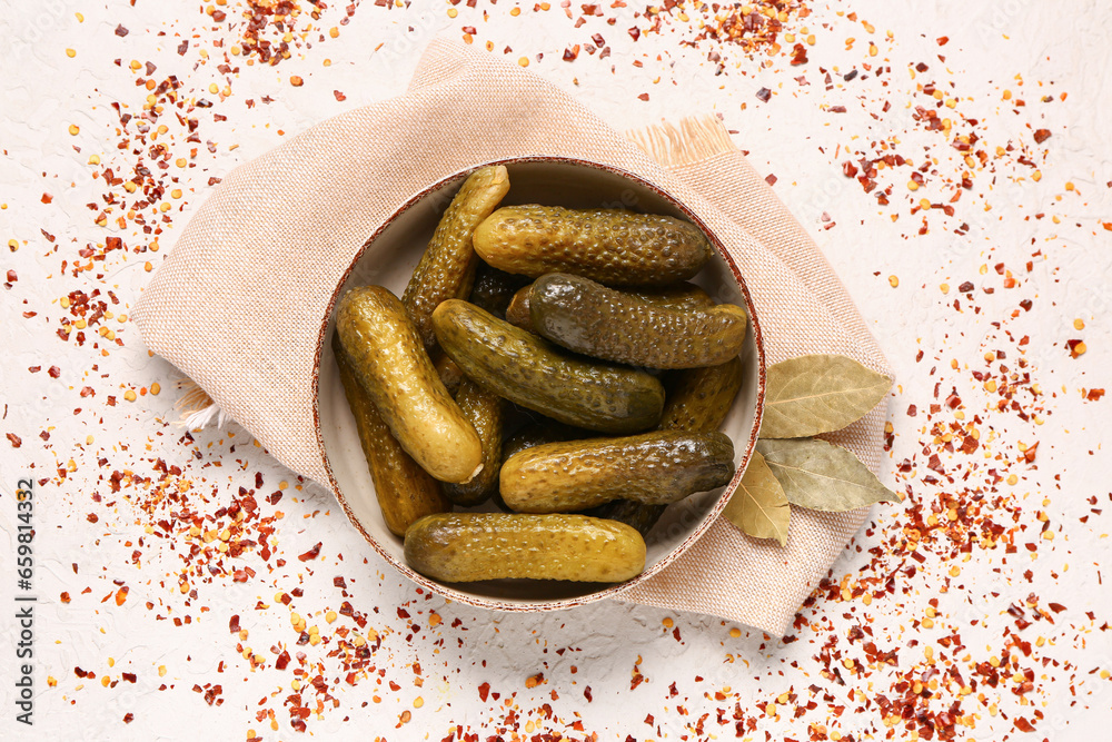 Bowl of tasty pickled cucumbers with bay leaves and spices on white background