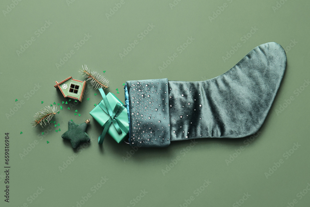 Beautiful Christmas sock with gift box and decorations on green background