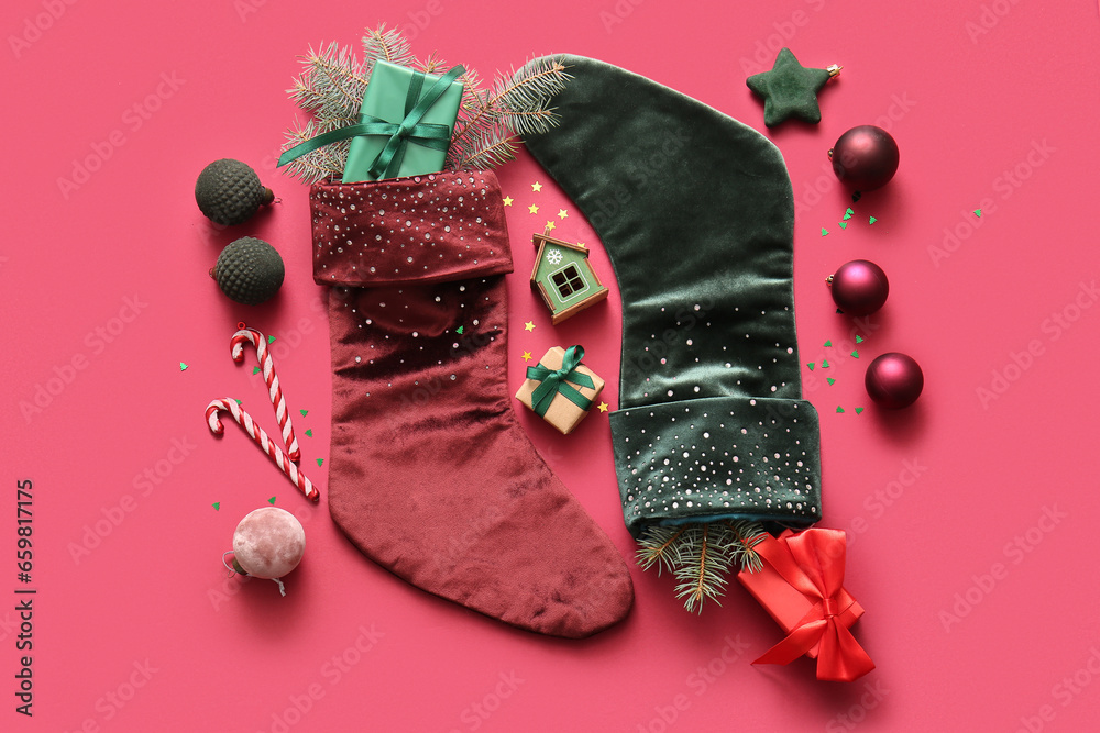 Beautiful Christmas socks with gift boxes and decorations on red background