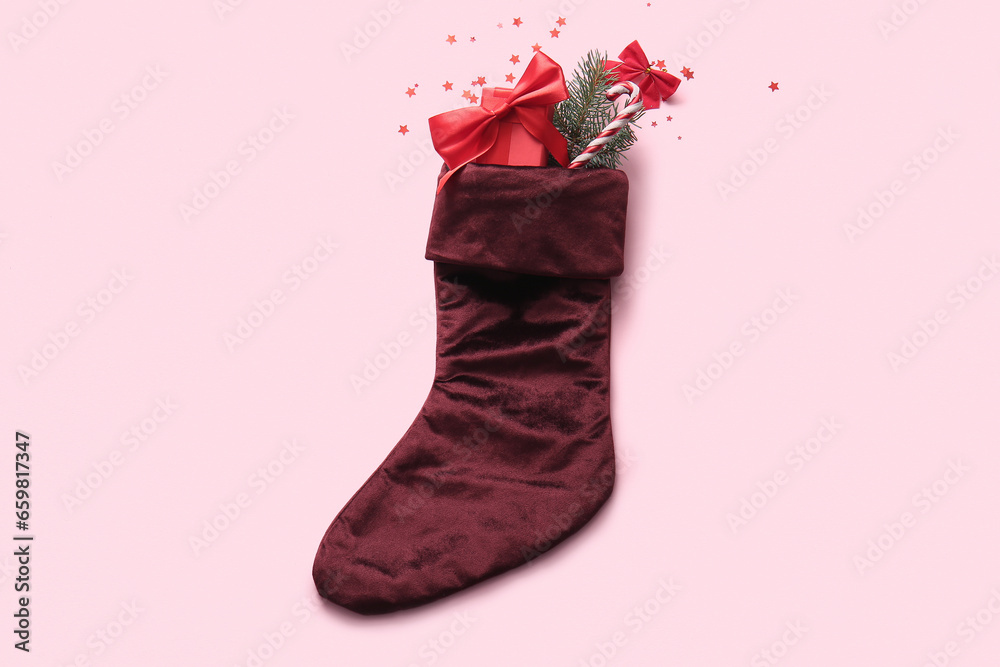 Beautiful Christmas sock with gift box and decorations on pink background