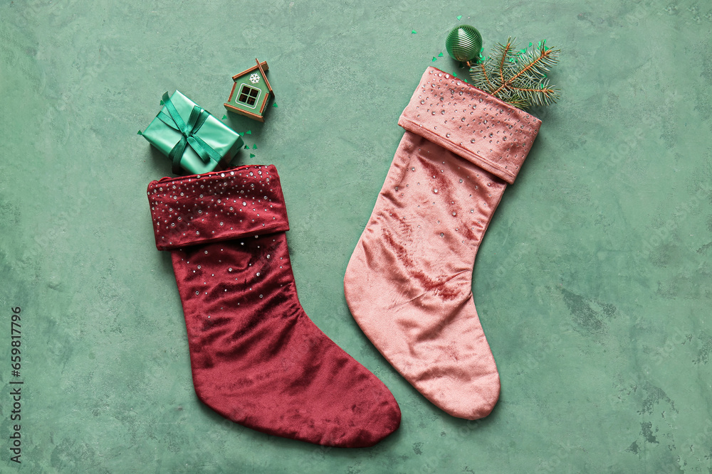 Beautiful Christmas socks with gift box and decorations on green background