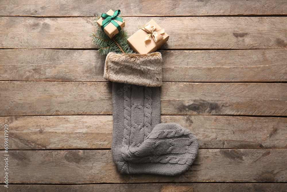 Beautiful Christmas sock with gift boxes and fir branch on wooden background