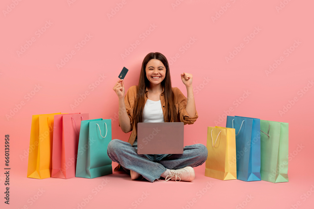 Teen Girl Celebrating Success With Laptop And Credit Card Among Shopping Bags