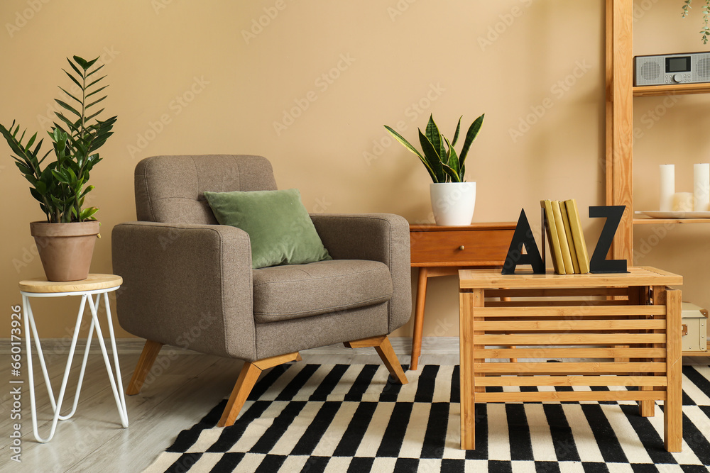 Interior of modern room with armchair and stylish holder for books on wooden table