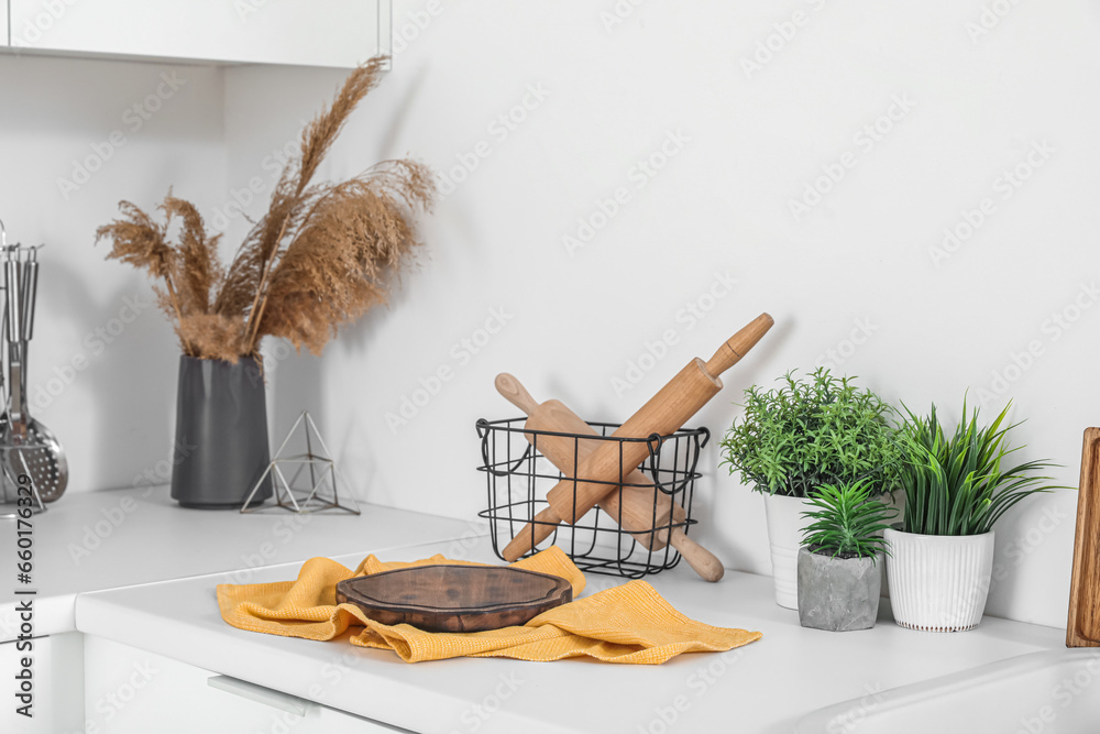 White kitchen countertop with cutting board, rolling pins and houseplant