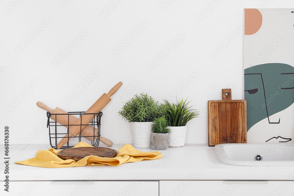 White kitchen countertop with cutting board, rolling pins and houseplant