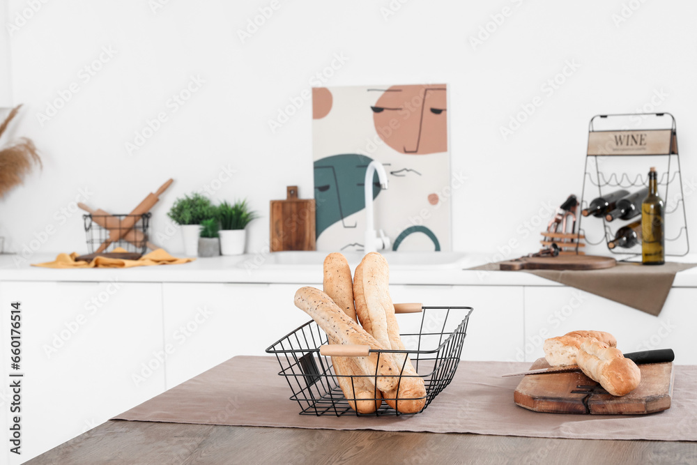 Cutting board with fresh baguette on table in interior of light kitchen