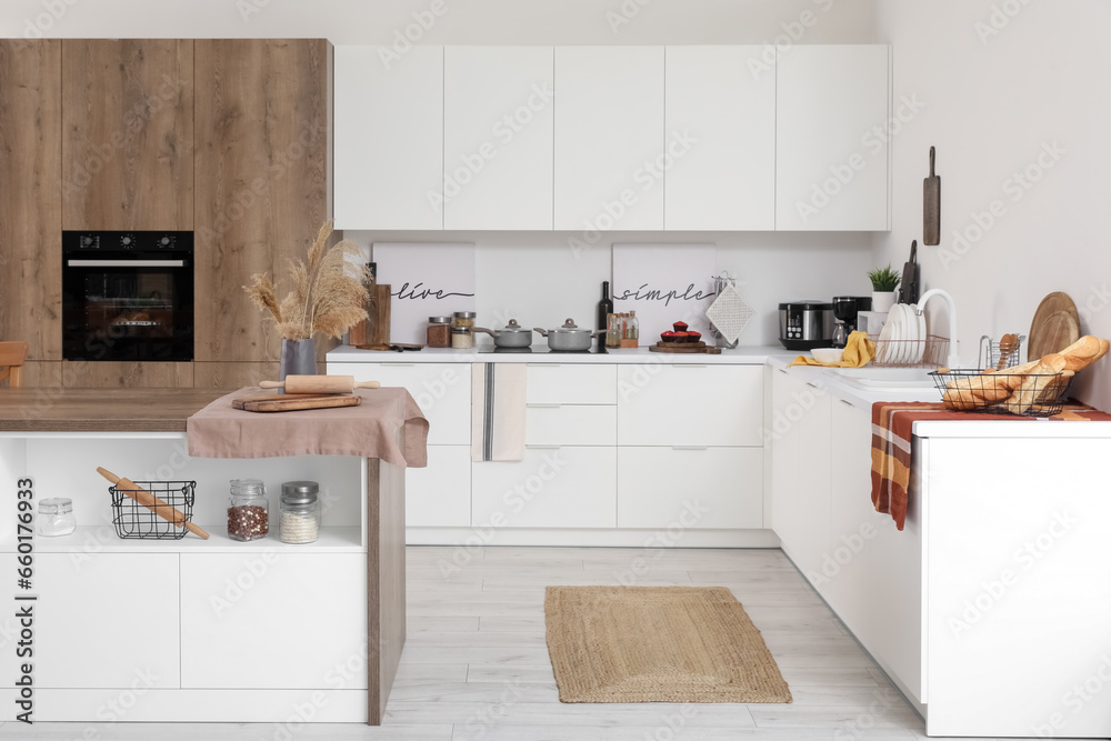 Interior of light kitchen with white counters and island table