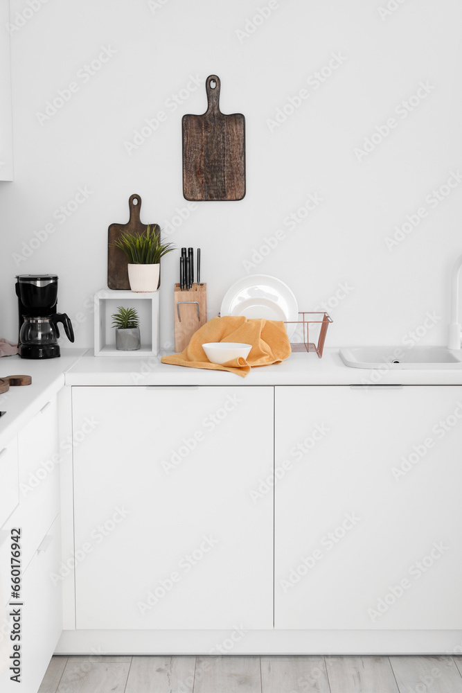 White kitchen counters with coffee machine, sink, plate rack and utensils