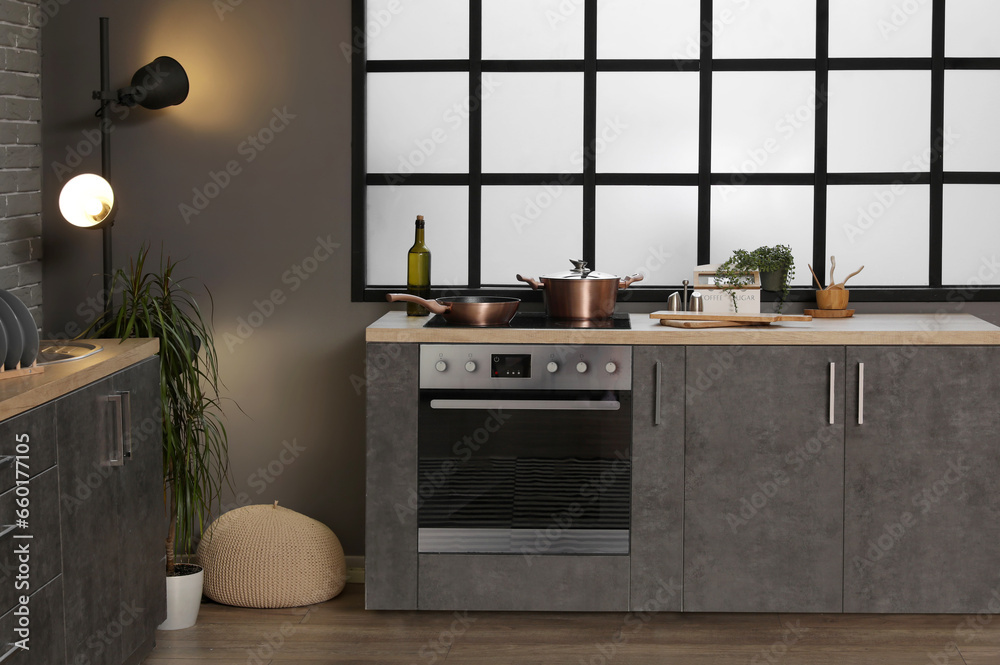 Interior of modern kitchen with grey counters and electric oven