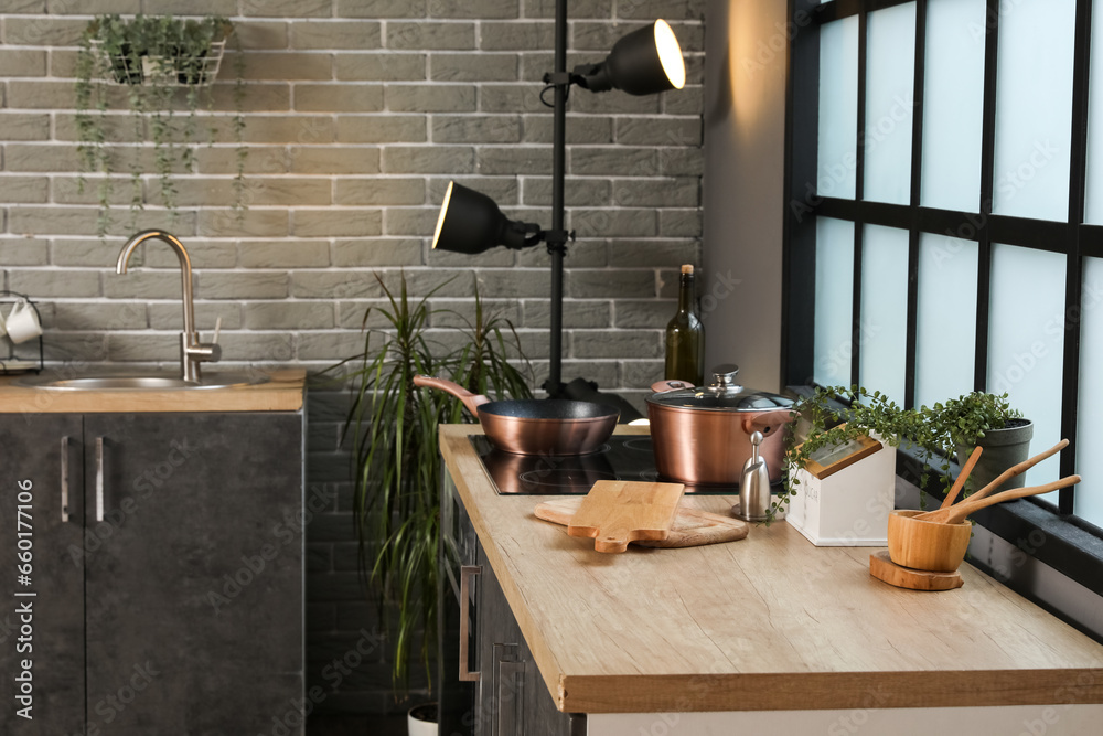 Wooden countertop with cutting boards, utensils and electric stove in modern kitchen