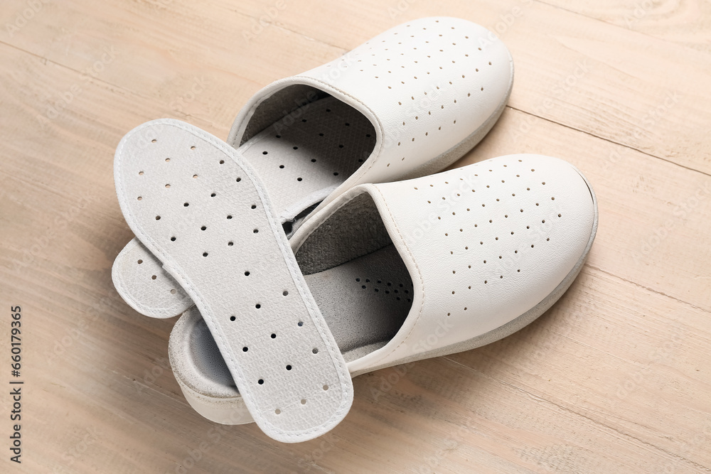 Pair of slippers and orthopedic insoles on wooden background