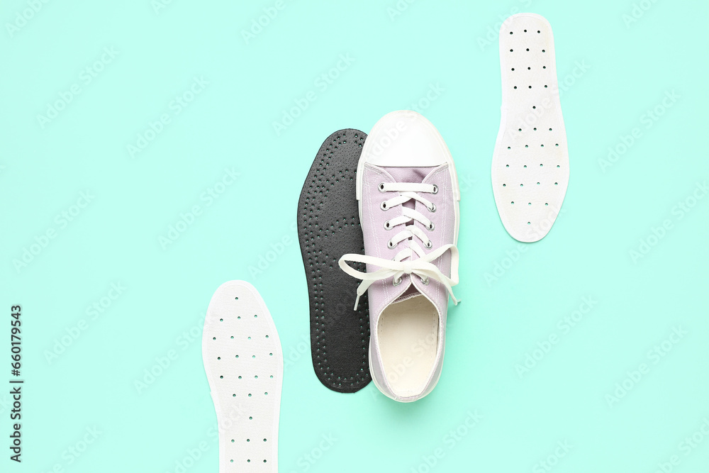 Composition with stylish gumshoe and different orthopedic insoles on color background