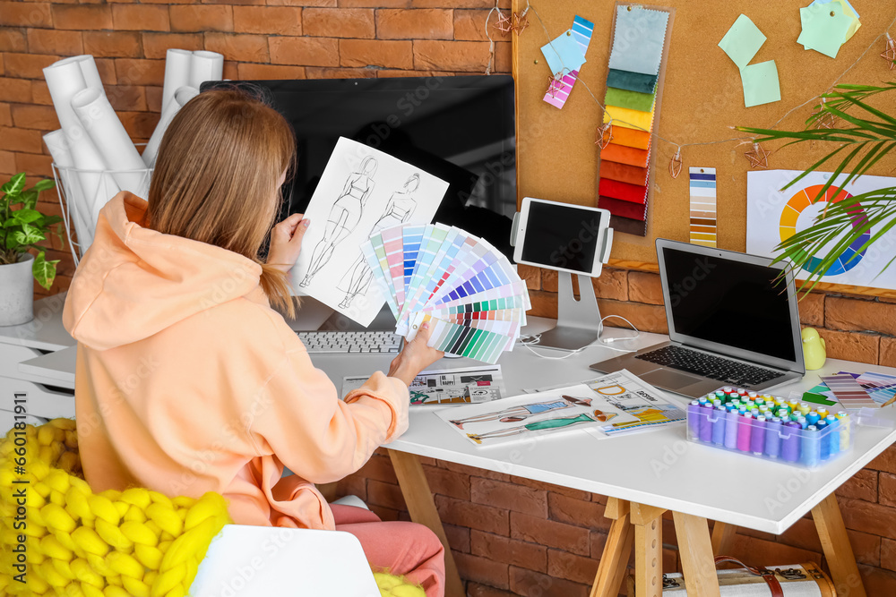 Female fashion designer working with color palettes at table in office