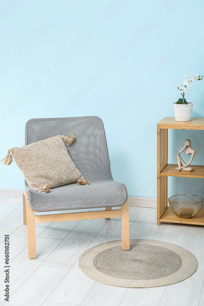 Comfortable armchair with cushion near color wall