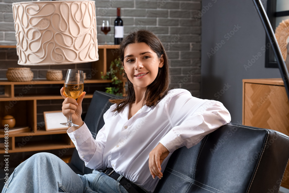 Young woman with glass of wine sitting on couch at home