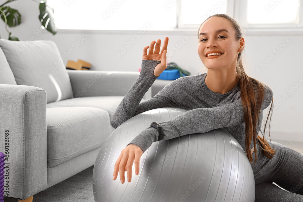 Sporty young woman training with fitball at home