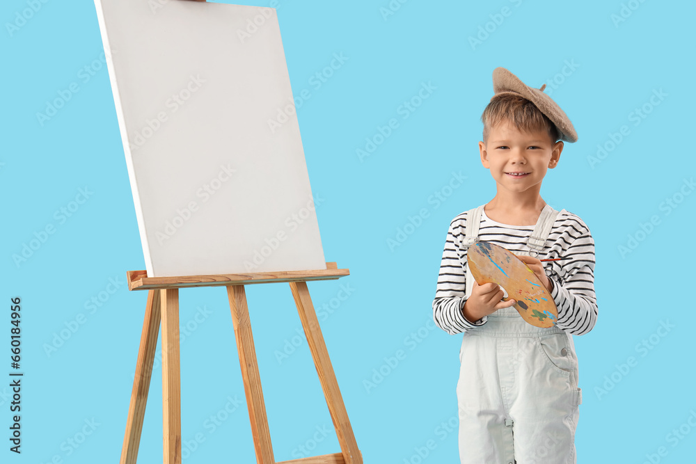 Cute little artist with paint palette and easel on blue background