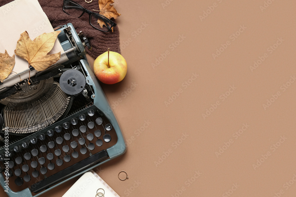 Vintage typewriter, apple, scarf, rings, eyeglasses and autumn leaves on brown background