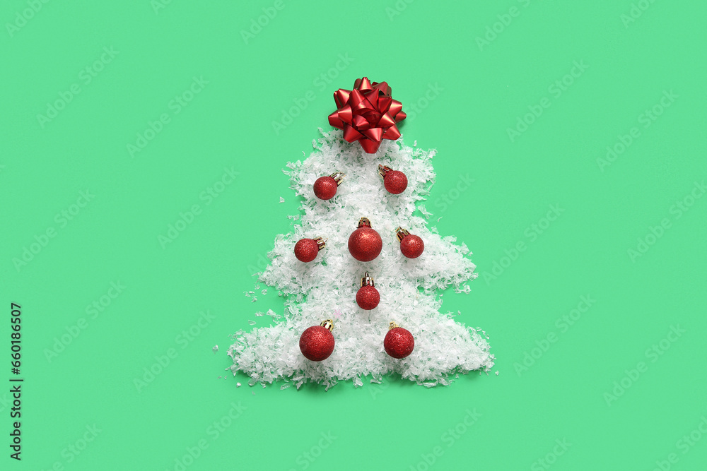 Christmas tree made of snow, balls and bow on green background