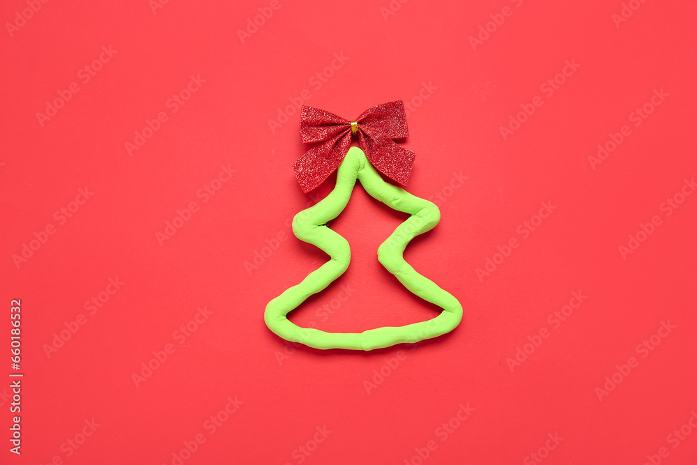 Christmas tree made of plasticine and bow on red background