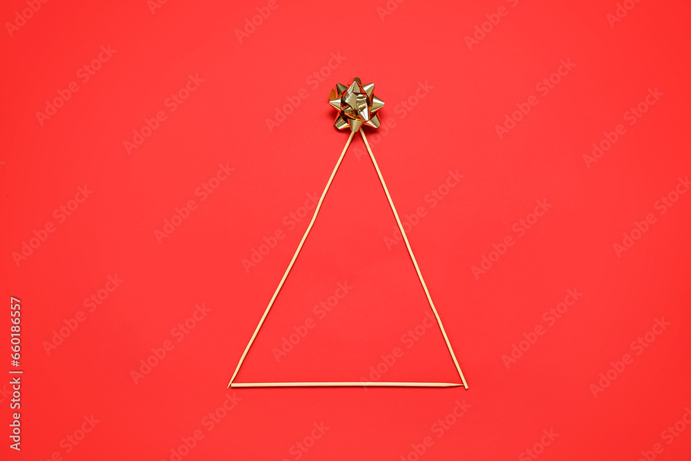 Christmas tree made of toothpicks and bow on red background