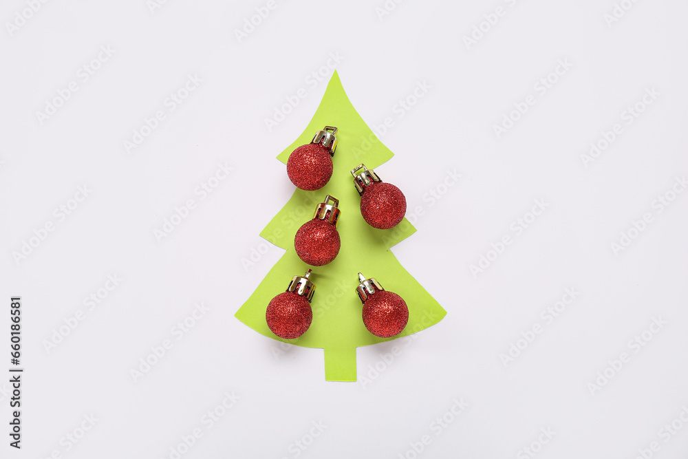 Cut green paper in shape of Christmas tree and balls on white background