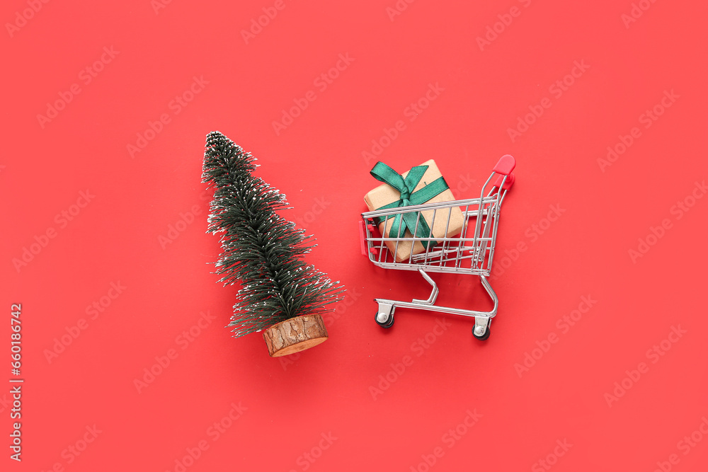 Shopping cart with Christmas tree and gift box on red background