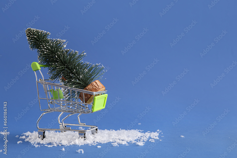 Shopping cart with Christmas tree and snow on blue background