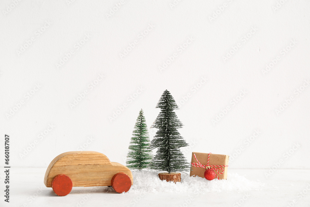 Wooden toy car with Christmas trees and gift box on white background