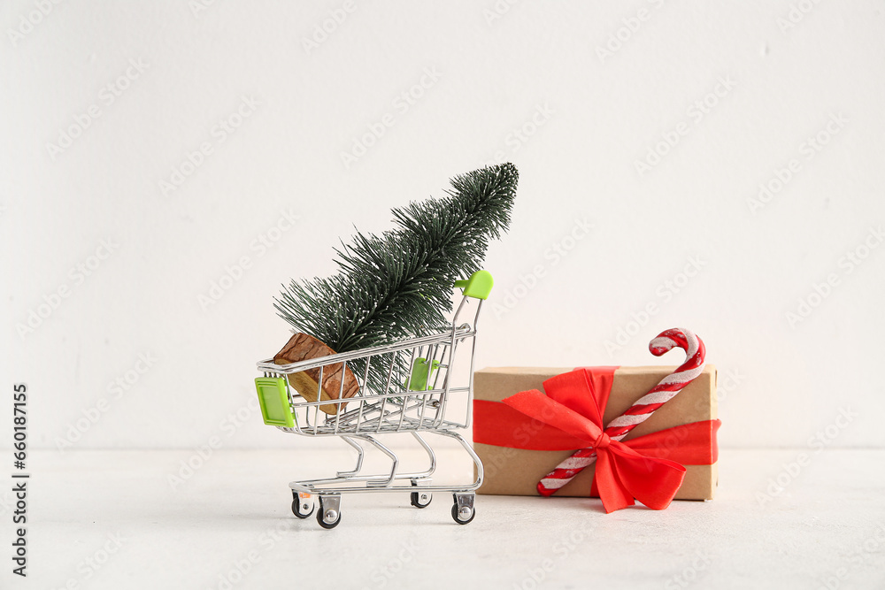 Shopping cart with Christmas tree and gift box on white background