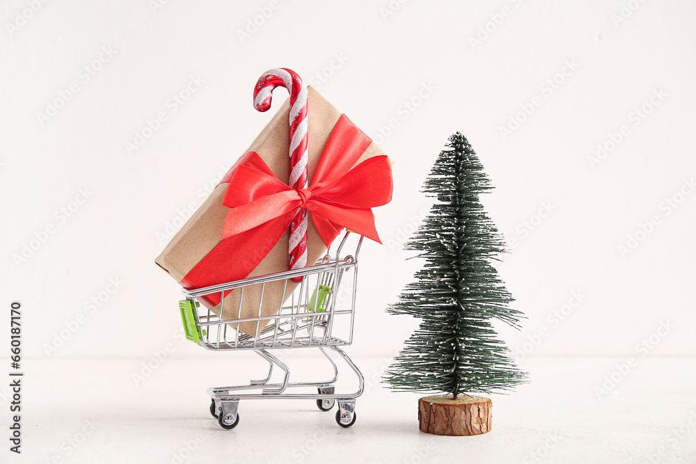 Shopping cart with Christmas tree and gift box on white background