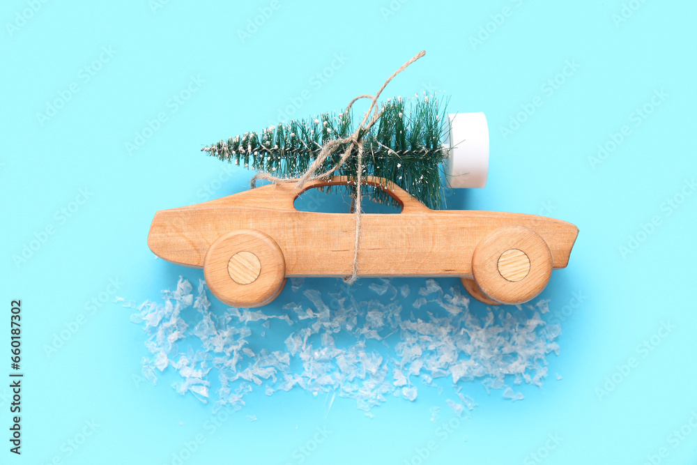 Christmas tree and wooden toy car on blue background