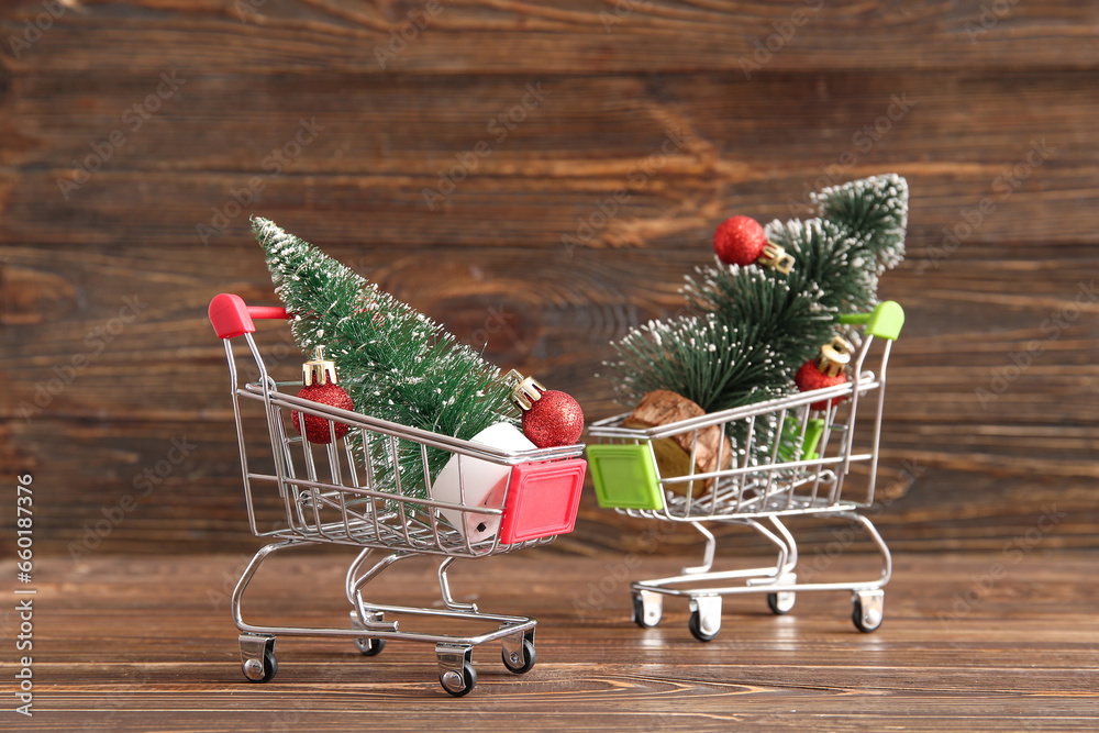 Shopping carts with Christmas trees and balls on wooden background