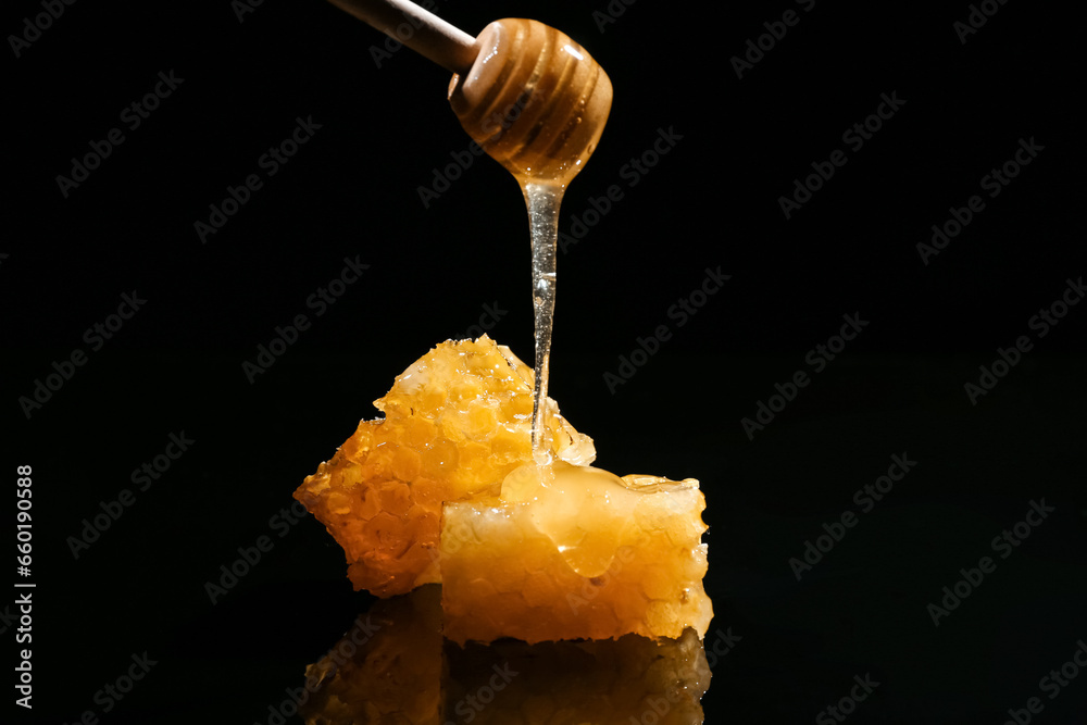 Sweet honeycombs and dipper on black background