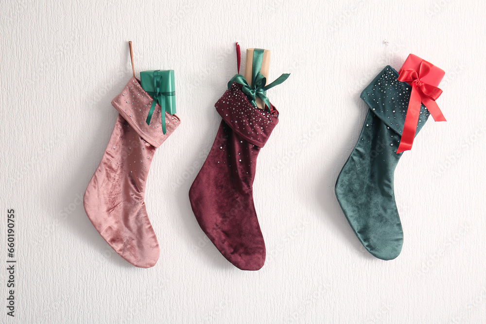 Beautiful Christmas socks with gift boxes hanging on white wall