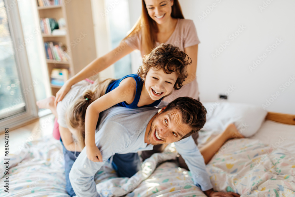 Happy young family playing and having fun on the bed at home