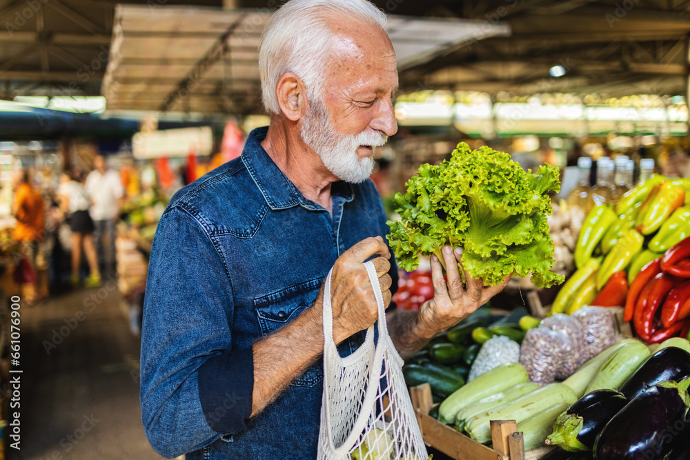 Eldery man buying vegetables at the market. Senior man buys organic vegetables at the market.