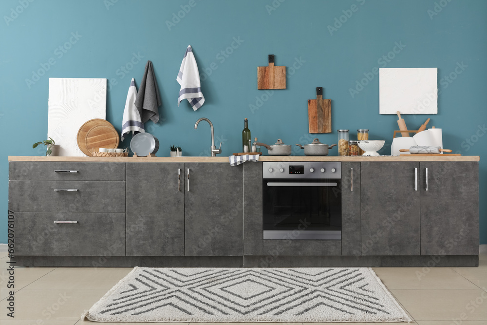 Interior of modern kitchen with grey counters, cutting boards, electric stove and oven