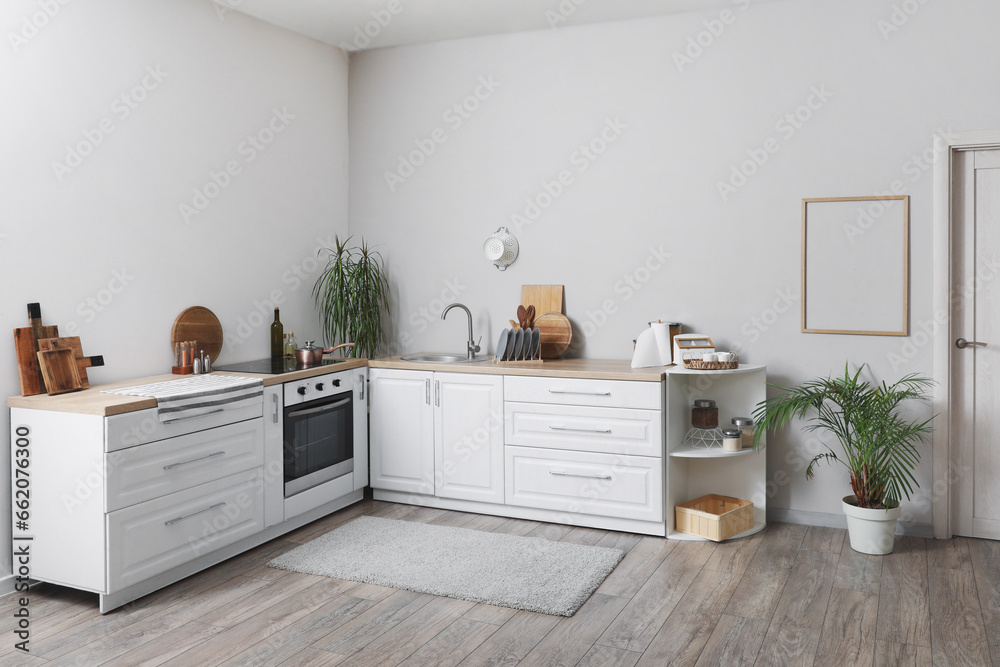 Interior of modern kitchen with white counters, oven and sink