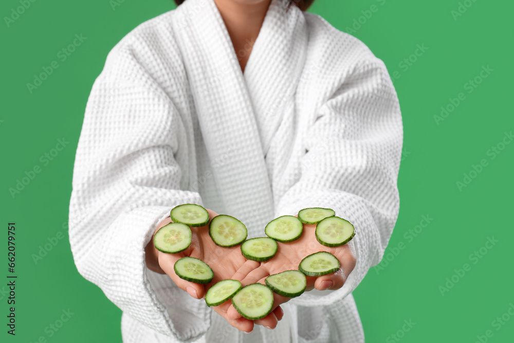 Young woman with heart made of cucumber slices on green background, closeup