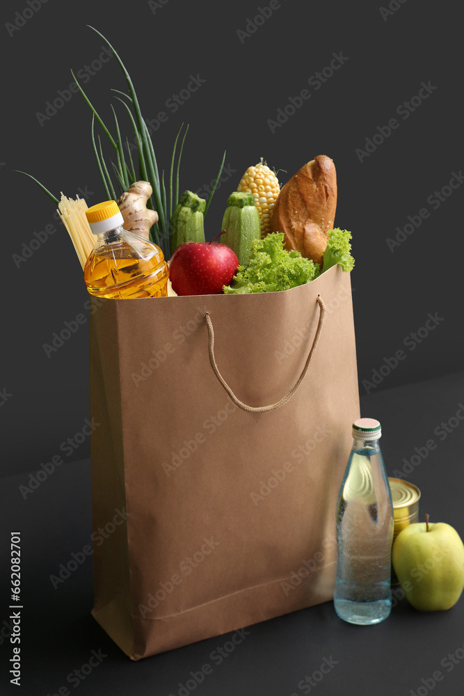 Paper shopping bag with different fresh products on black background