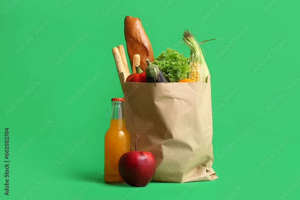 Paper shopping bag with different fresh products on green background