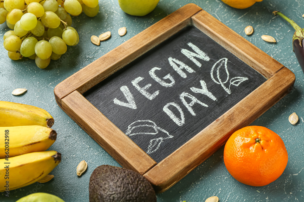 Board with text VEGAN DAY and different fresh fruits on blue background