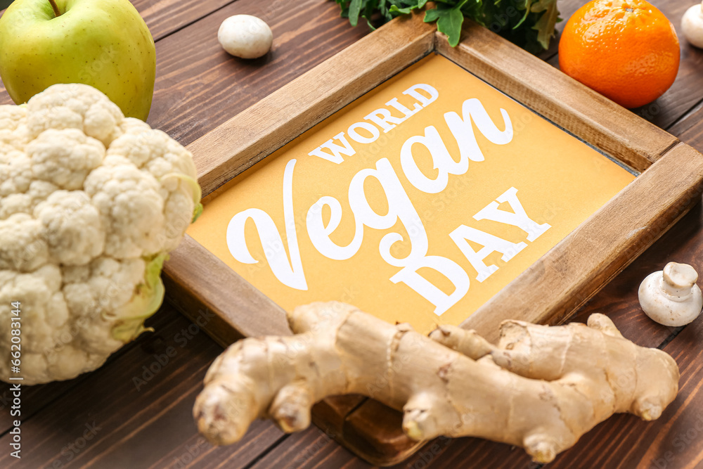 Board with text WORLD VEGAN DAY and different fresh vegetables on wooden background