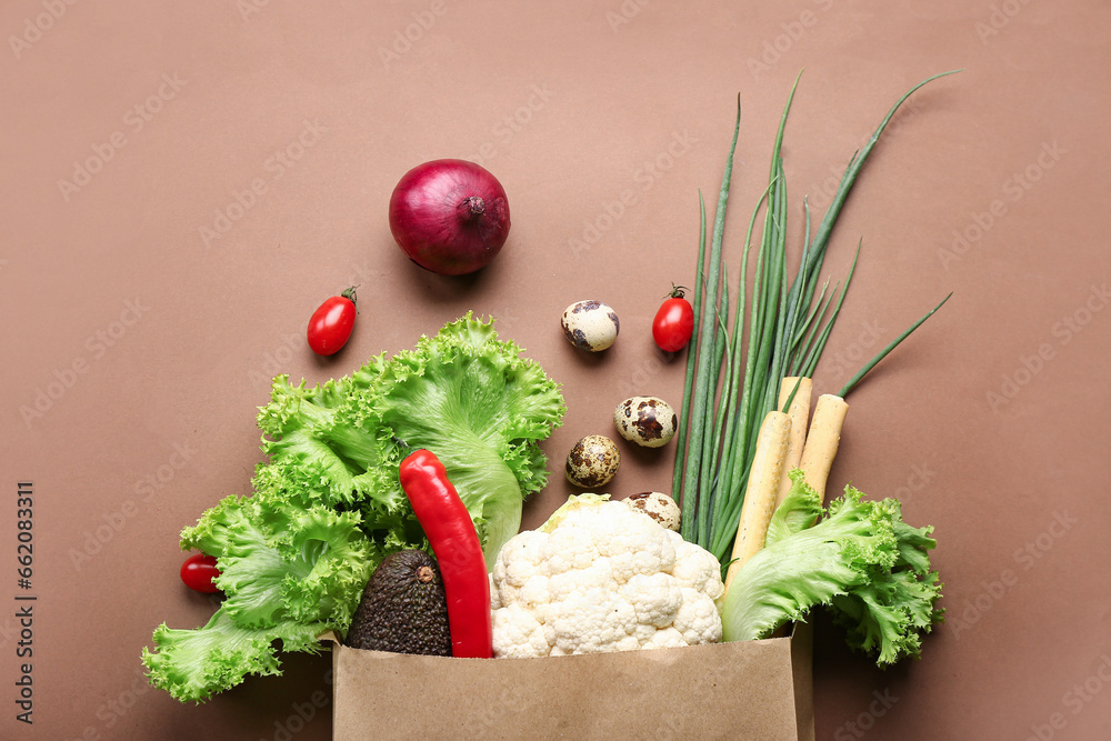 Paper shopping bag with fresh vegetables on brown background