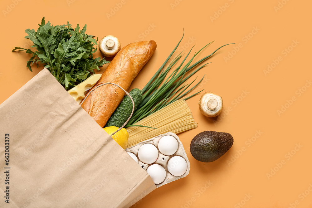 Paper shopping bag with different fresh products on orange background