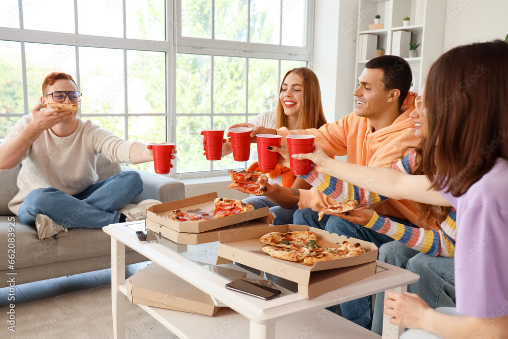 Group of young friends with pizza drinking at home party