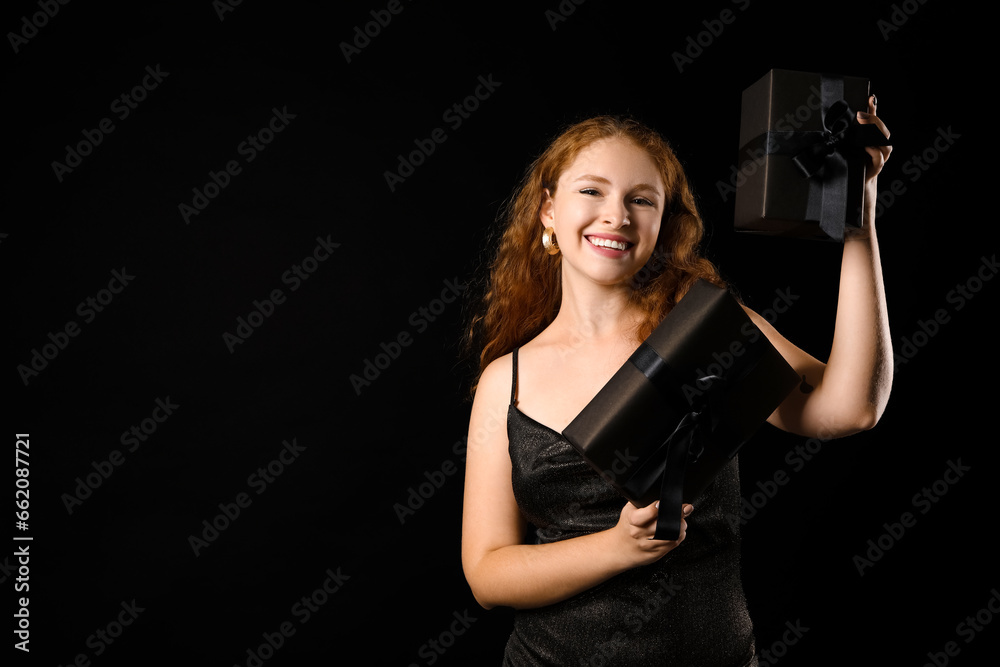 Beautiful young woman with gift boxes on dark background. Black Friday sale