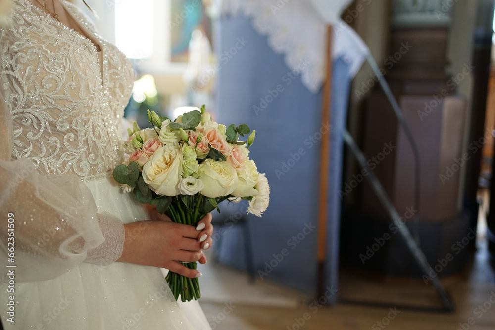 During the wedding ceremony, the bride holds a beautiful white bouquet of flowers in her hand.